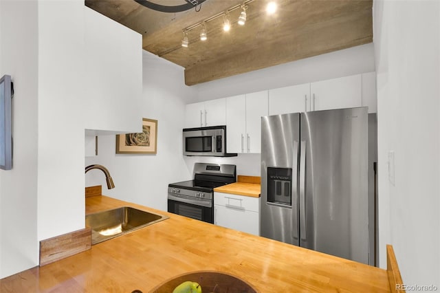 kitchen with wood counters, white cabinets, a sink, and stainless steel appliances