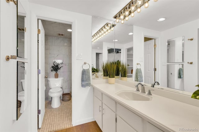 bathroom featuring visible vents, toilet, vanity, recessed lighting, and tile walls