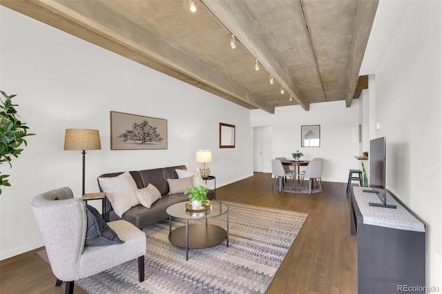 living area featuring dark wood-type flooring, rail lighting, baseboards, and beam ceiling