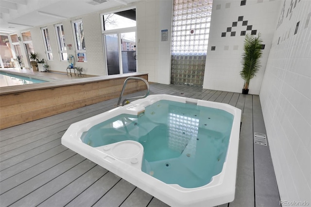 view of swimming pool featuring a deck and an indoor hot tub