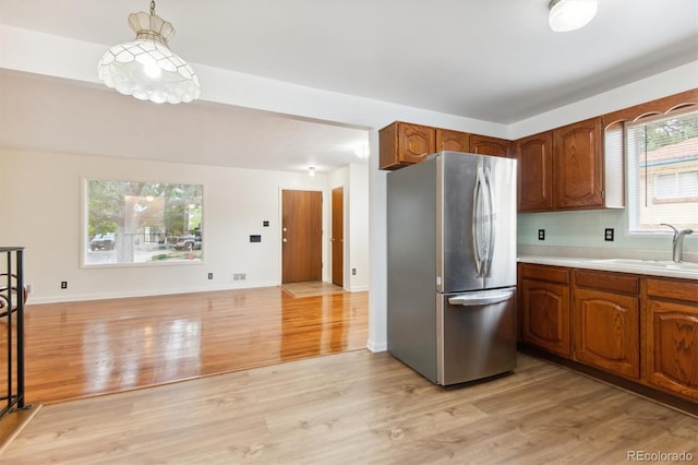 7886 Cyd Dr, Denver, CO 80221 - kitchen with light wood-type flooring, light countertops, a sink, and freestanding refrigerator