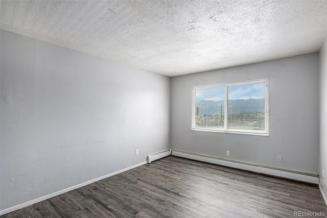 spare room featuring a baseboard heating unit, dark wood-type flooring, and a textured ceiling