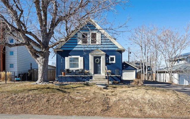 view of front of house featuring driveway, a front lawn, a detached garage, and fence