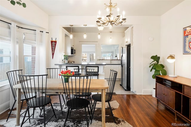 dining area with a notable chandelier, baseboards, dark wood-style flooring, and a wealth of natural light