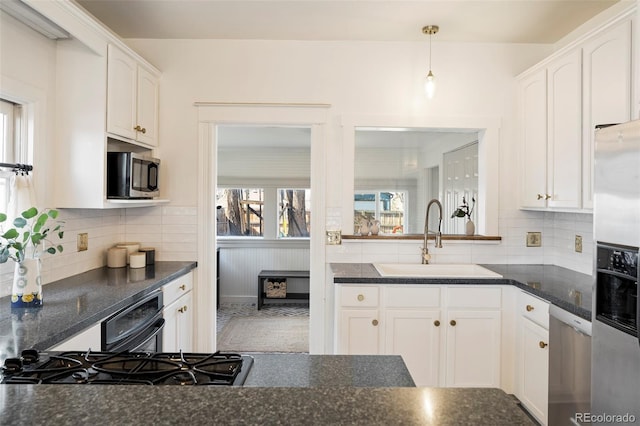 kitchen with appliances with stainless steel finishes, a sink, white cabinetry, and decorative backsplash