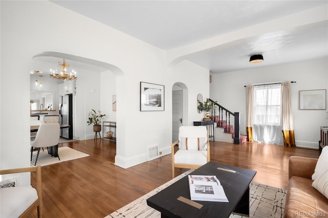 5103 Quitman St, Denver, CO 80212 - living room featuring arched walkways, stairs, wood finished floors, and a chandelier