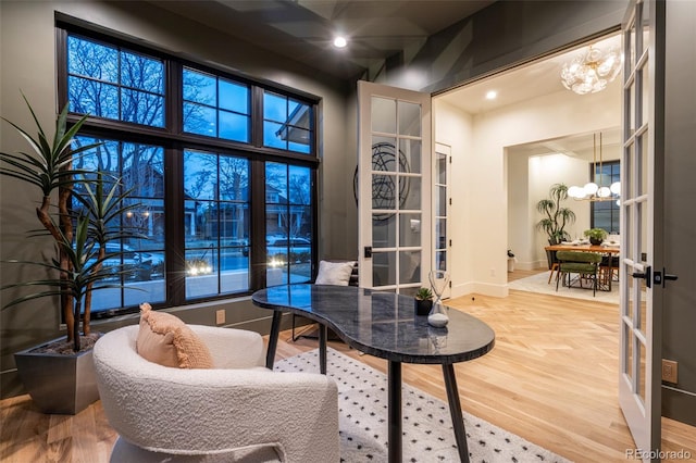 office featuring french doors, light wood-style flooring, and a notable chandelier