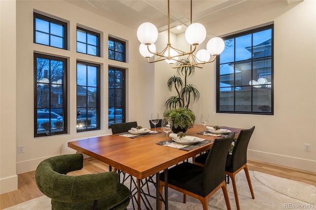 dining space with a notable chandelier, baseboards, and light wood-style floors