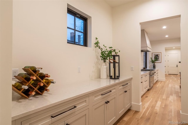 bar with custom exhaust hood, recessed lighting, light wood-style flooring, high end stove, and baseboards