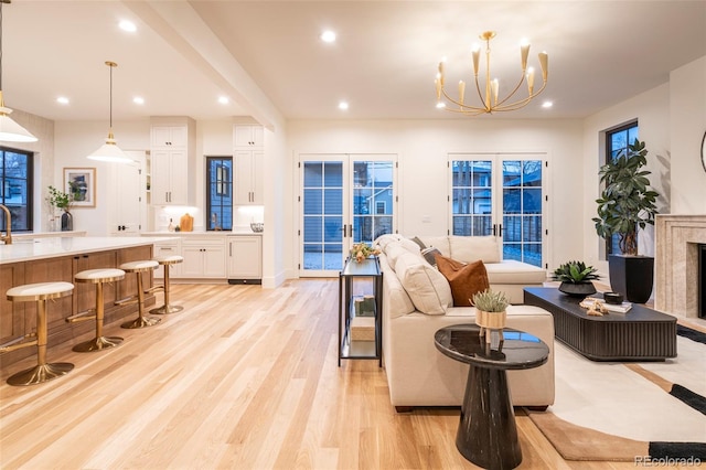 living room with french doors, a fireplace, light wood-style flooring, and recessed lighting