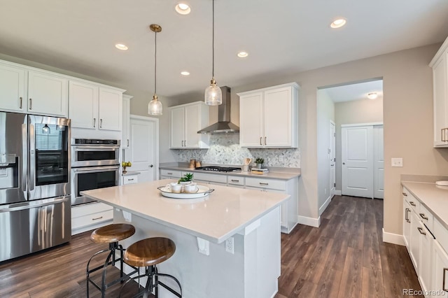 38 Morgan Cir, Erie, CO 80516 - kitchen featuring appliances with stainless steel finishes, wall chimney range hood, white cabinetry, a center island, and recessed lighting