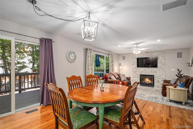 9640 Moss Rose Cir, Highlands Ranch, CO 80129 - dining area featuring light wood finished floors, a large fireplace, ceiling fan, and a chandelier