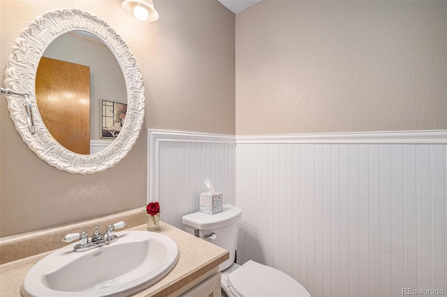 9640 Moss Rose Cir, Highlands Ranch, CO 80129 - half bath featuring a wainscoted wall, vanity, and a textured wall