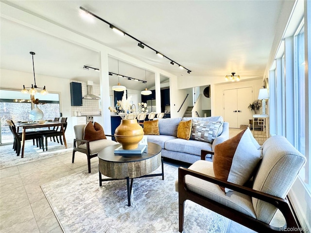 living room featuring light tile patterned flooring, a healthy amount of sunlight, and an inviting chandelier