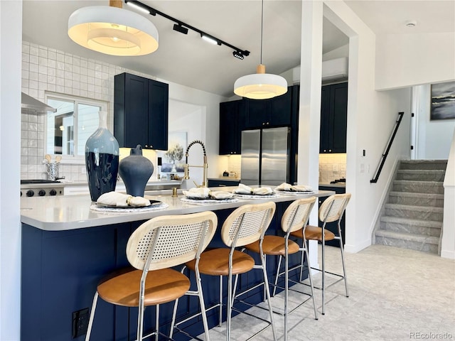 kitchen featuring a kitchen breakfast bar, decorative backsplash, stainless steel refrigerator, and kitchen peninsula