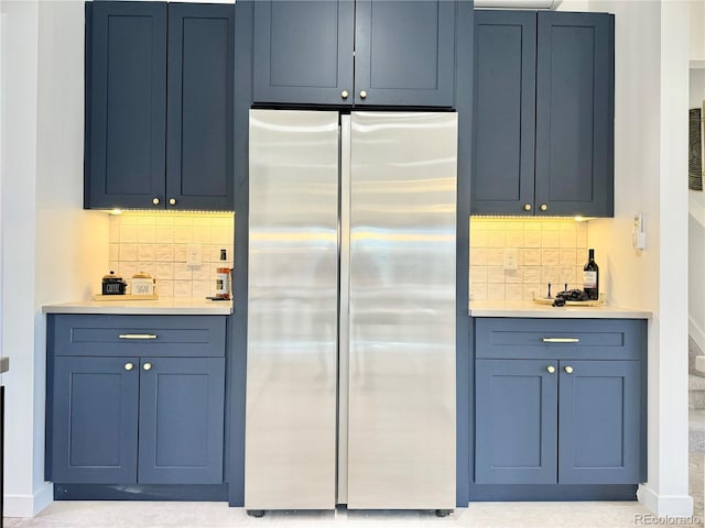 kitchen featuring tasteful backsplash, blue cabinetry, and stainless steel refrigerator