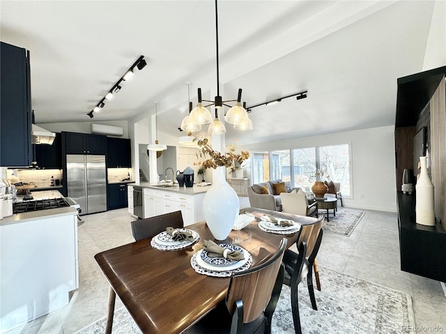 dining area with rail lighting, lofted ceiling, and sink