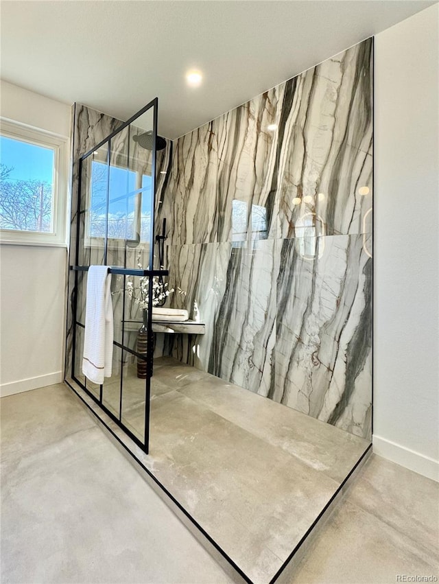 bathroom with concrete flooring and tiled shower