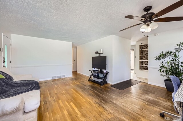 living room featuring hardwood / wood-style flooring, ceiling fan, and a textured ceiling