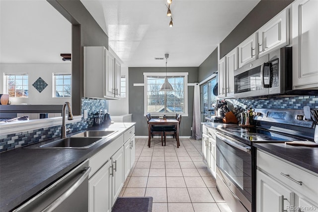 kitchen with white cabinetry, sink, stainless steel appliances, decorative light fixtures, and light tile patterned floors