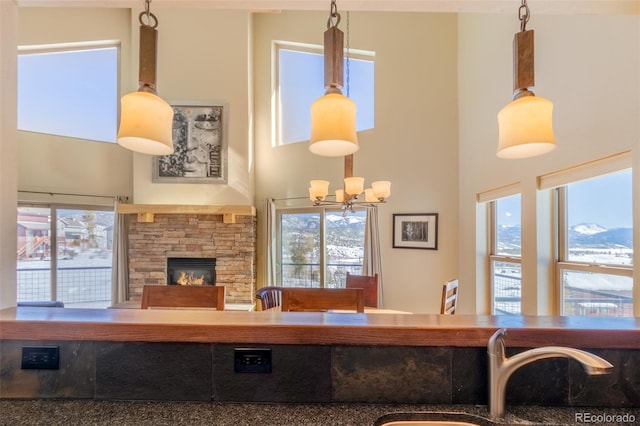 living area with a towering ceiling, an inviting chandelier, and a stone fireplace