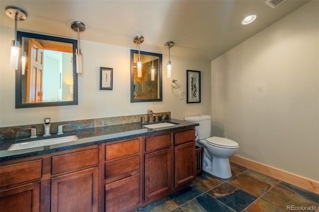 bathroom featuring baseboards, a sink, toilet, and double vanity