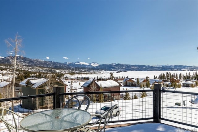 snow covered back of property featuring a residential view, a mountain view, and outdoor dining area