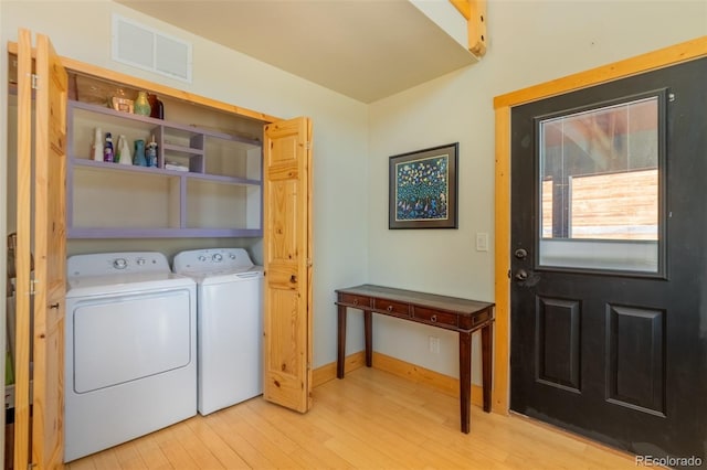 clothes washing area with laundry area, light wood finished floors, visible vents, baseboards, and washing machine and dryer