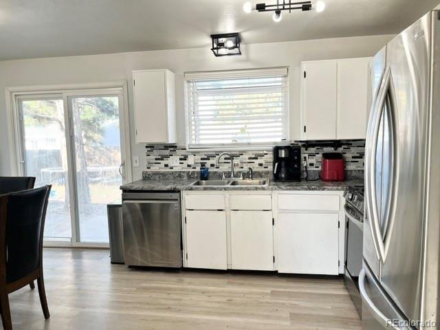 kitchen with sink, light hardwood / wood-style flooring, decorative backsplash, white cabinetry, and stainless steel appliances