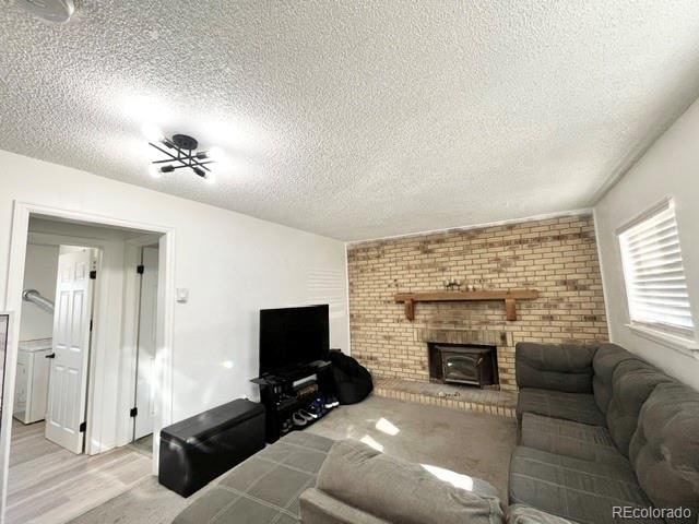 living room with a wood stove, a textured ceiling, and light wood-type flooring