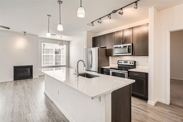9185 Wilde Ln Unit 301, Parker, CO 80134 - kitchen with appliances with stainless steel finishes, a sink, light wood-style flooring, light countertops, and an island with sink