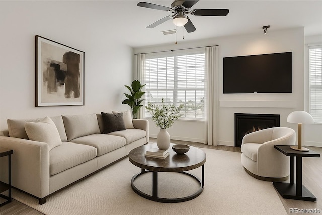 9185 Wilde Ln Unit 301, Parker, CO 80134 - living room featuring a ceiling fan, wood finished floors, and a lit fireplace