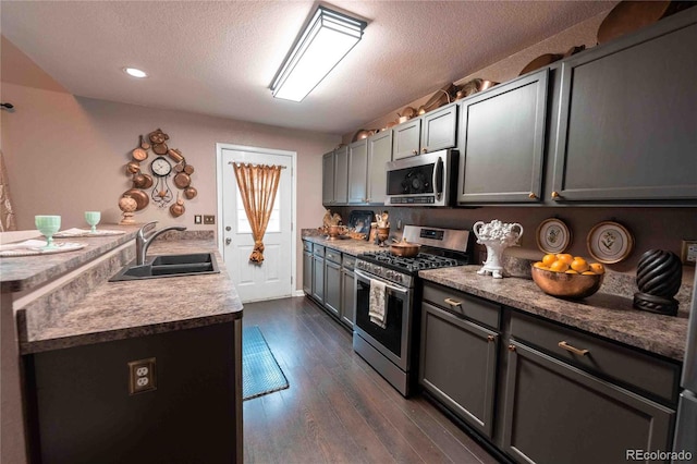 12242 Bannock Cir Unit D, Denver, CO 80234 - kitchen with stainless steel appliances, a sink, a textured ceiling, dark wood-type flooring, and a peninsula