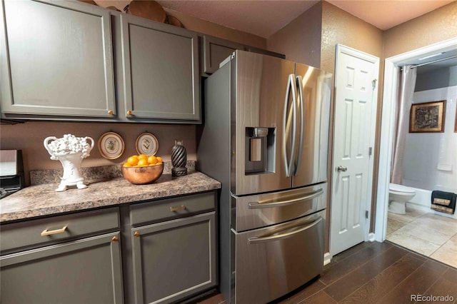 12242 Bannock Cir Unit D, Denver, CO 80234 - kitchen featuring stainless steel fridge, gray cabinetry, dark wood-type flooring, and light stone counters