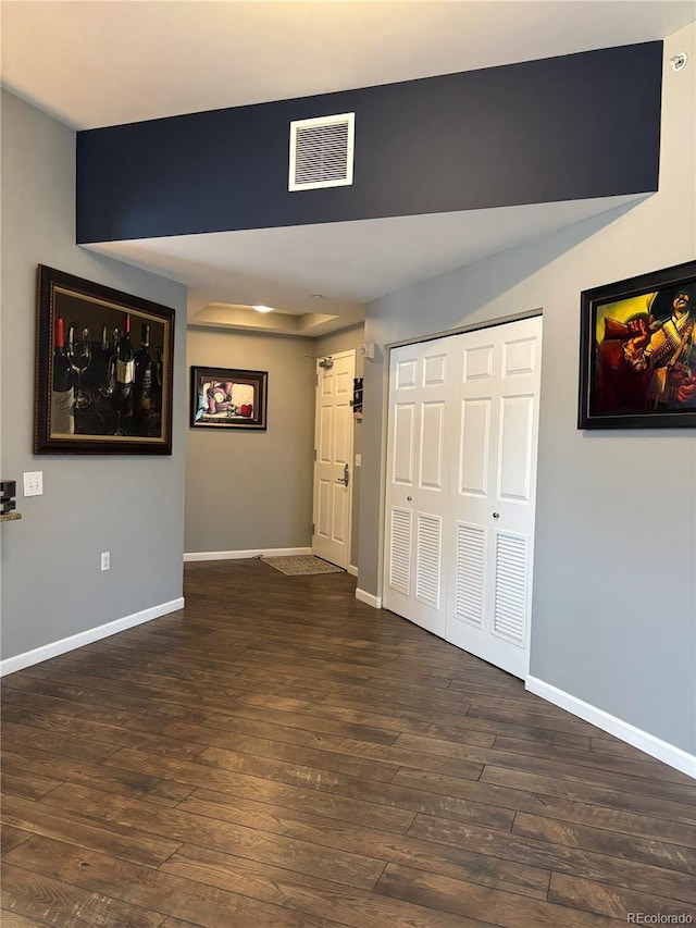 interior space with dark wood-style floors, visible vents, and baseboards