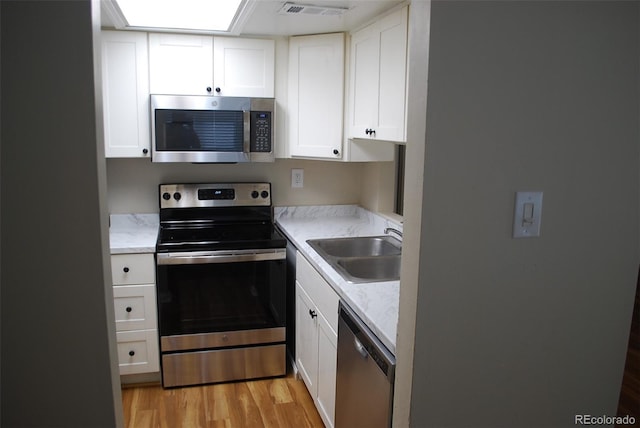 kitchen with visible vents, light wood finished floors, a sink, appliances with stainless steel finishes, and white cabinetry