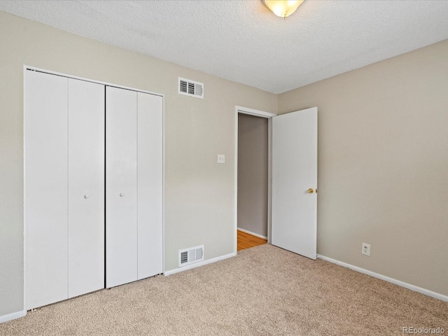 unfurnished bedroom with a closet, visible vents, a textured ceiling, and carpet floors