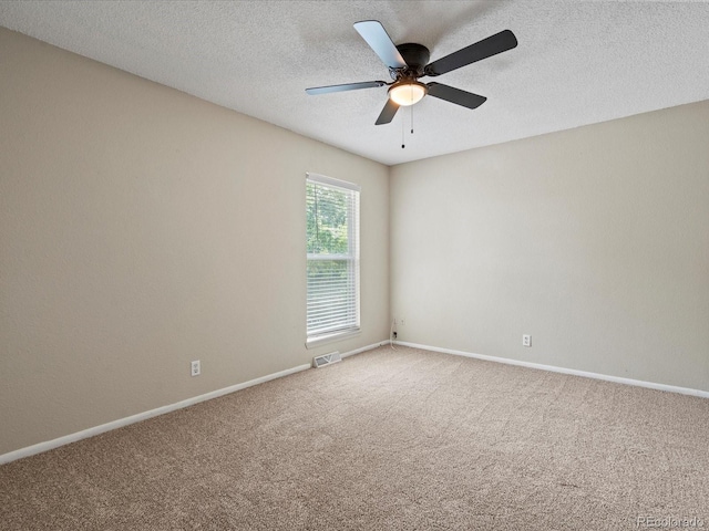 empty room with visible vents, a ceiling fan, a textured ceiling, carpet floors, and baseboards