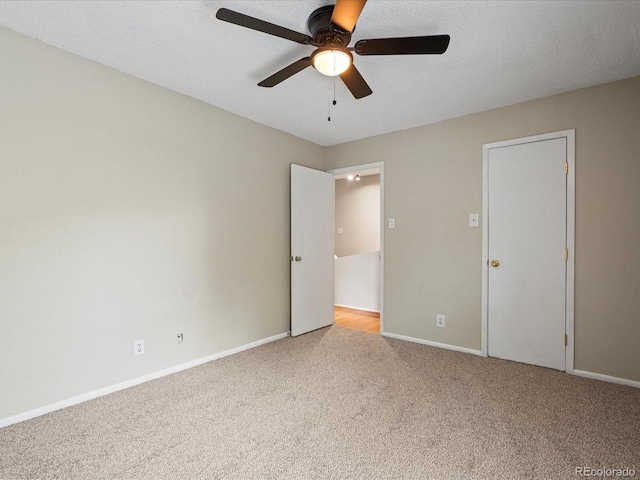 unfurnished bedroom with carpet flooring, ceiling fan, a textured ceiling, and baseboards