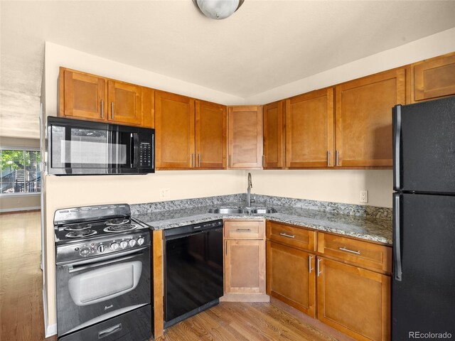 61 S Sable Blvd Unit C15, Aurora, CO 80012 - kitchen with black appliances, a sink, light wood-type flooring, light stone counters, and brown cabinets