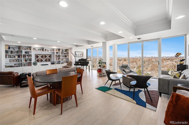 dining space featuring a tray ceiling, a wealth of natural light, light wood-style flooring, and crown molding