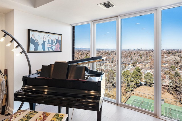 living area with expansive windows, a wealth of natural light, wood finished floors, and visible vents