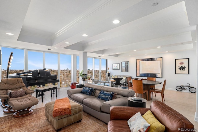 living area featuring a raised ceiling, ornamental molding, wood finished floors, and recessed lighting