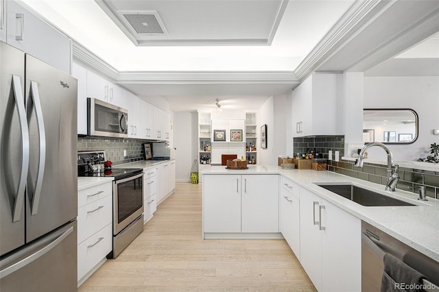 kitchen featuring stainless steel appliances, a tray ceiling, a sink, and visible vents