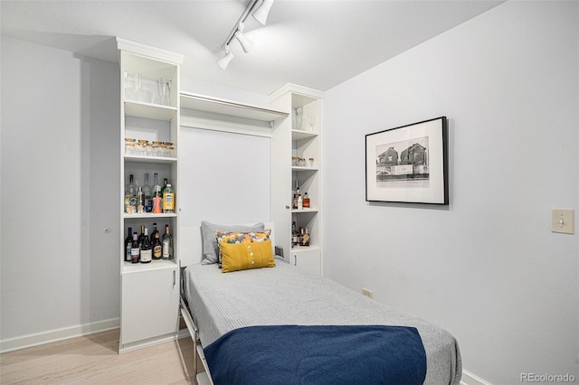 bedroom featuring light wood-style floors, rail lighting, and baseboards