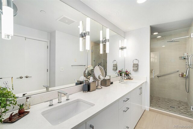 full bathroom with double vanity, a sink, visible vents, and a shower stall