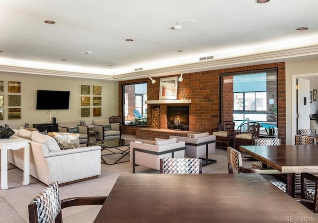 living area featuring light carpet, a fireplace, visible vents, and crown molding