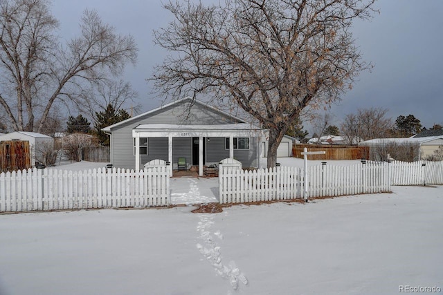 snow covered back of property featuring a garage and an outdoor structure