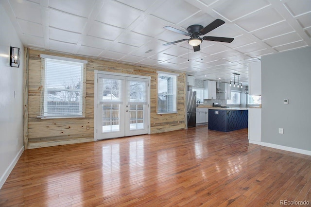 unfurnished living room with wood-type flooring, french doors, wood walls, ceiling fan, and coffered ceiling