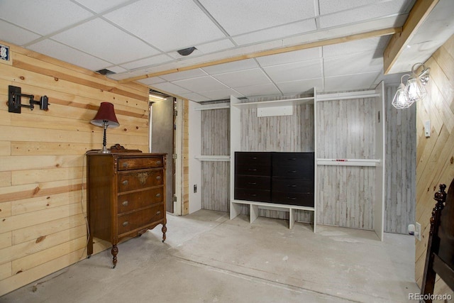 basement featuring a drop ceiling and wooden walls